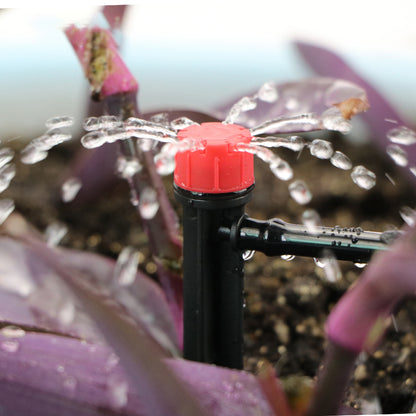 Close-up of automatic garden irrigation system sprinkler head watering purple plants in soil