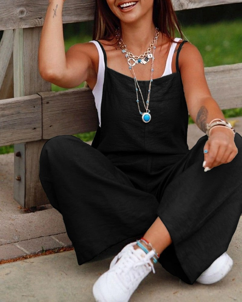 Casual black fashion jumpsuit for women with wide legs and thin straps paired with white sneakers