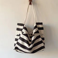 Striped canvas shoulder bag with black and white artistic contrast color stripes hanging on wall